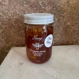 Jar of honey with a silver lid on a countertop