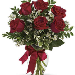 Bouquet of red roses with baby's breath in a glass vase tied with a red ribbon