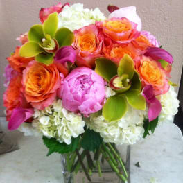 Colorful bouquet of roses, peonies, hydrangeas, and orchids in a glass vase