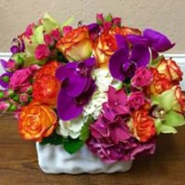 Colorful bouquet of roses and purple orchids in a white vase