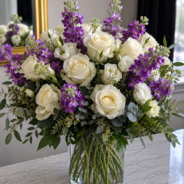 White roses and purple flowers in a clear glass vase