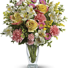 Mixed bouquet of roses, carnations, alstroemeria, and yellow filler flowers in a glass vase
