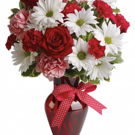 Bouquet of red roses, pink carnations, and white daisies in a red vase