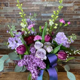 Purple and lavender bouquet in a glass vase with a ribbon