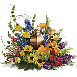 Mixed bouquet around a bronze urn with yellow, blue, orange, and purple flowers