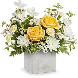 Arrangement of yellow roses and mixed white flowers in a gray cube vase