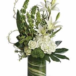 White lilies and roses in a green glass vase