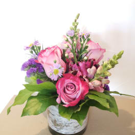 Pink roses and purple flowers arranged in a small vase