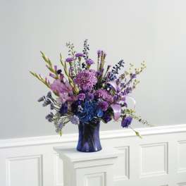 Purple and blue floral arrangement in a dark blue vase