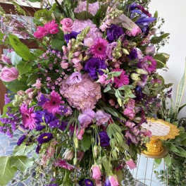 Large standing floral spray in pink, purple, and lavender tones