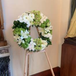 White and green floral wreath on a wooden easel