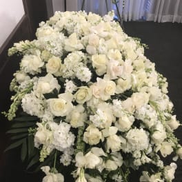 Large white floral casket spray with roses and orchids