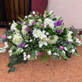 Large floral arrangement with white lilies, roses, and purple blooms
