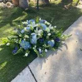 Blue and white floral arrangement placed beside a walkway outdoors