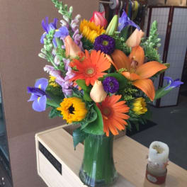 Colorful mixed bouquet in a glass vase with lilies and gerbera daisies