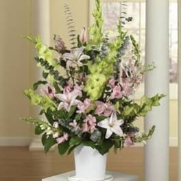 Tall floral arrangement in a white pot with pink lilies and greenery