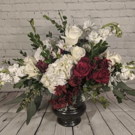 Large floral arrangement of white and deep red flowers in a black vase