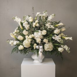 White floral arrangement with roses, calla lilies, and hydrangeas in a white vase
