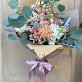 Hand-tied bouquet of pastel flowers with eucalyptus and a lavender ribbon