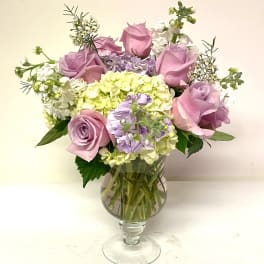 Pink roses and pastel hydrangeas arranged in a clear glass vase