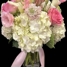 Pink and white bouquet in a glass vase with a pink ribbon