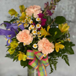 Mixed bouquet with purple lilies, peach carnations, and yellow flowers in a vase