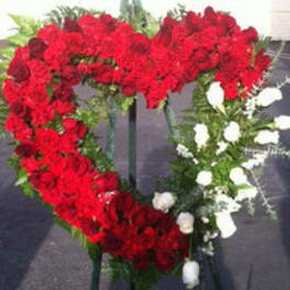 Heart-shaped floral wreath with red and white roses on a stand