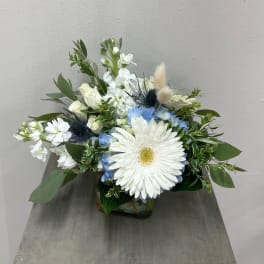 White and blue floral arrangement in a glass vase