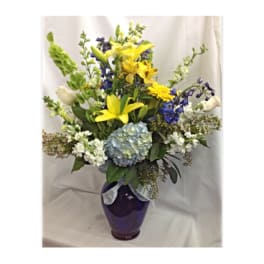 Yellow lilies and blue flowers in a purple vase