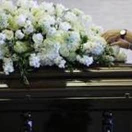 White floral spray on top of a dark casket