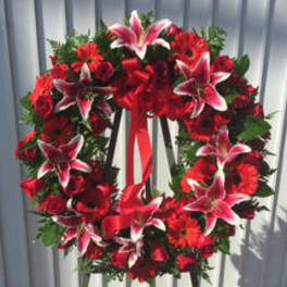 Red floral wreath with lilies and roses on a stand