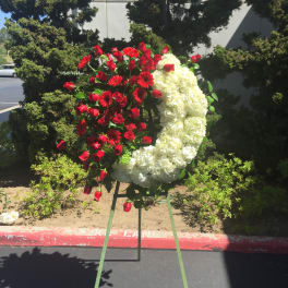Red roses and white flowers arranged in a crescent on a stand