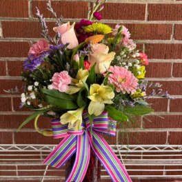 Mixed bouquet in a glass vase with a striped ribbon