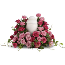 Pink and magenta roses arranged around a white urn.