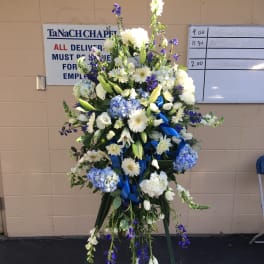 Tall standing floral spray with white and blue flowers on a tripod easel