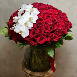 Bouquet of red roses with white orchids in a glass vase