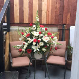 Large white and red floral arrangement in a vase on a stand