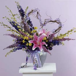 Pink lilies in a vase with purple and yellow flowers