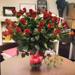Bouquet of red roses in a glass vase with a pink ribbon