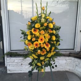 Tall yellow and orange floral standing spray on an easel