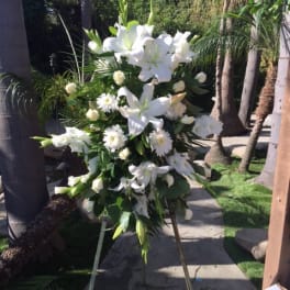White funeral spray on an easel with lilies and daisies