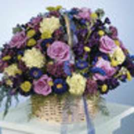 Large mixed flower arrangement in a woven basket with a ribbon