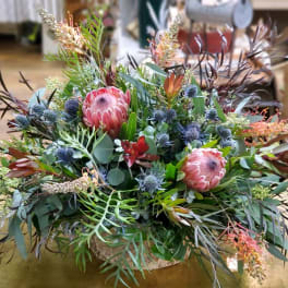 Large mixed floral arrangement with pink protea in a low container