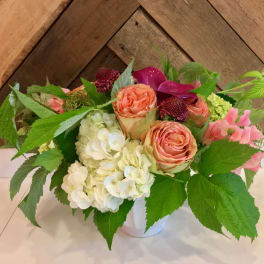 Bouquet of peach roses and white hydrangeas in a white vase