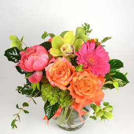 Bouquet of orange roses, pink gerbera daisies, and green orchids in a glass vase