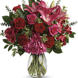 Bouquet of pink lilies and red roses in a clear glass vase