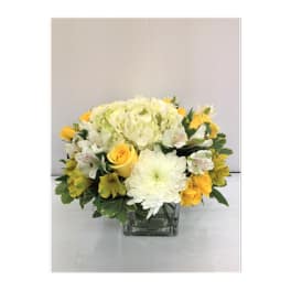 Yellow and white flower arrangement in a square glass vase