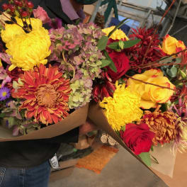 Two colorful mixed flower bouquets wrapped in brown paper