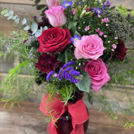 Bouquet of pink and red roses in a dark vase with a red ribbon