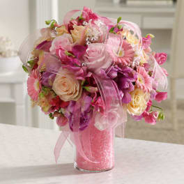 Pink and peach rose and gerbera daisy bouquet with purple blooms in a glass vase with pink beads